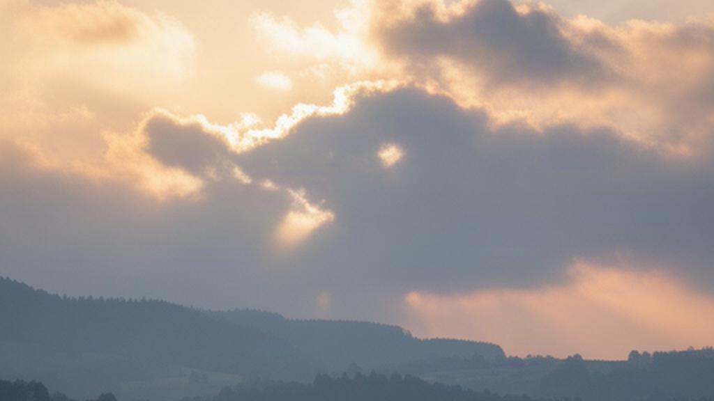 Morgenlicht bricht durch Wolken über den Dächern und Hügeln bei Deutschlandsberg