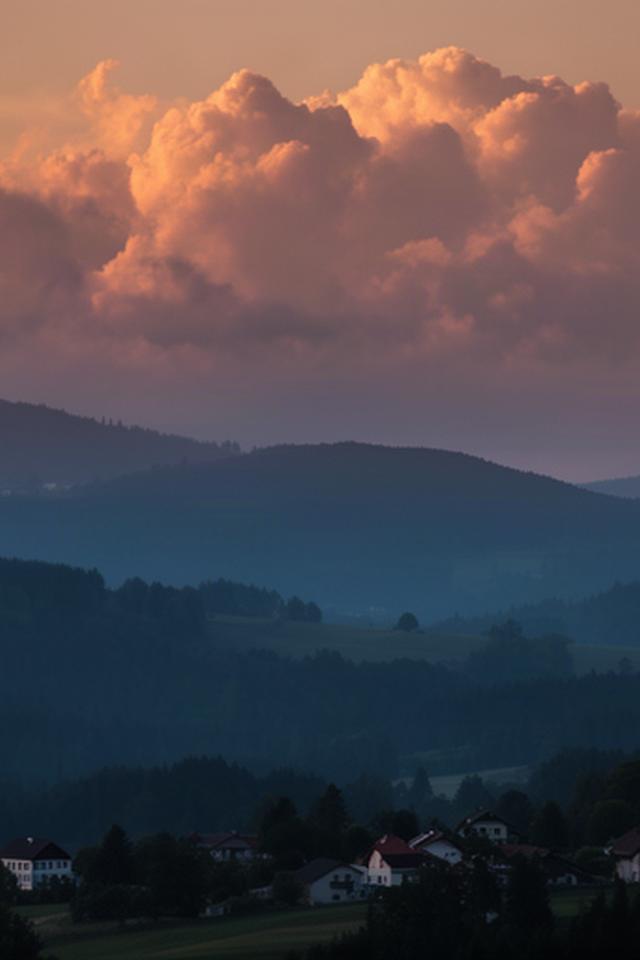 Abendliche Wolkenstimmung über einem kleinen Ort und den Hügeln der Weststeiermark