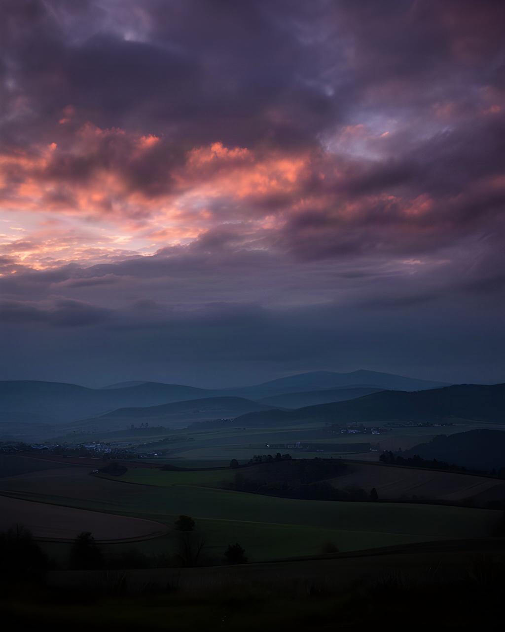 Abendwolken färben den Himmel über einer steirischen Hügellandschaft