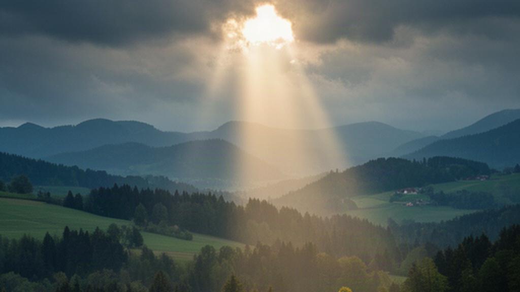 Sonnenlicht fällt durch Wolken auf Wiesen und Wälder im steirischen Hügelland